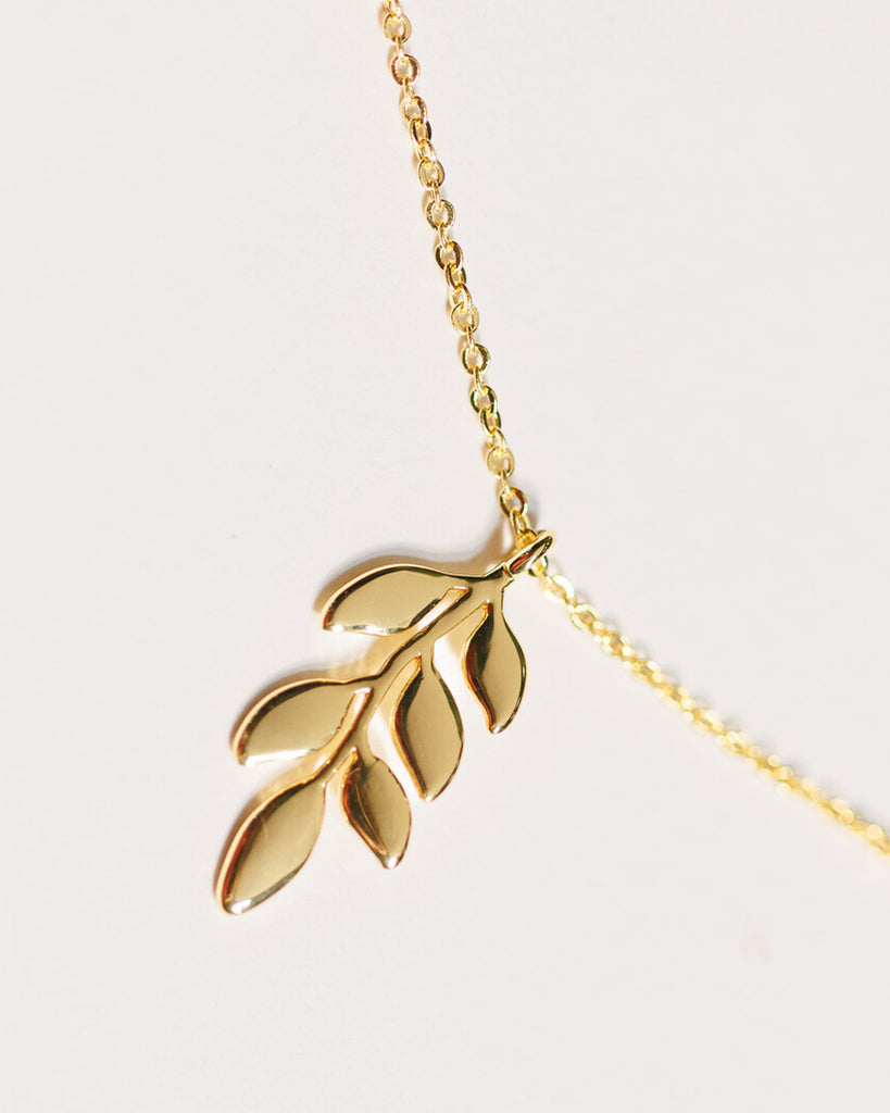 A gold necklace with a leaf pendant.