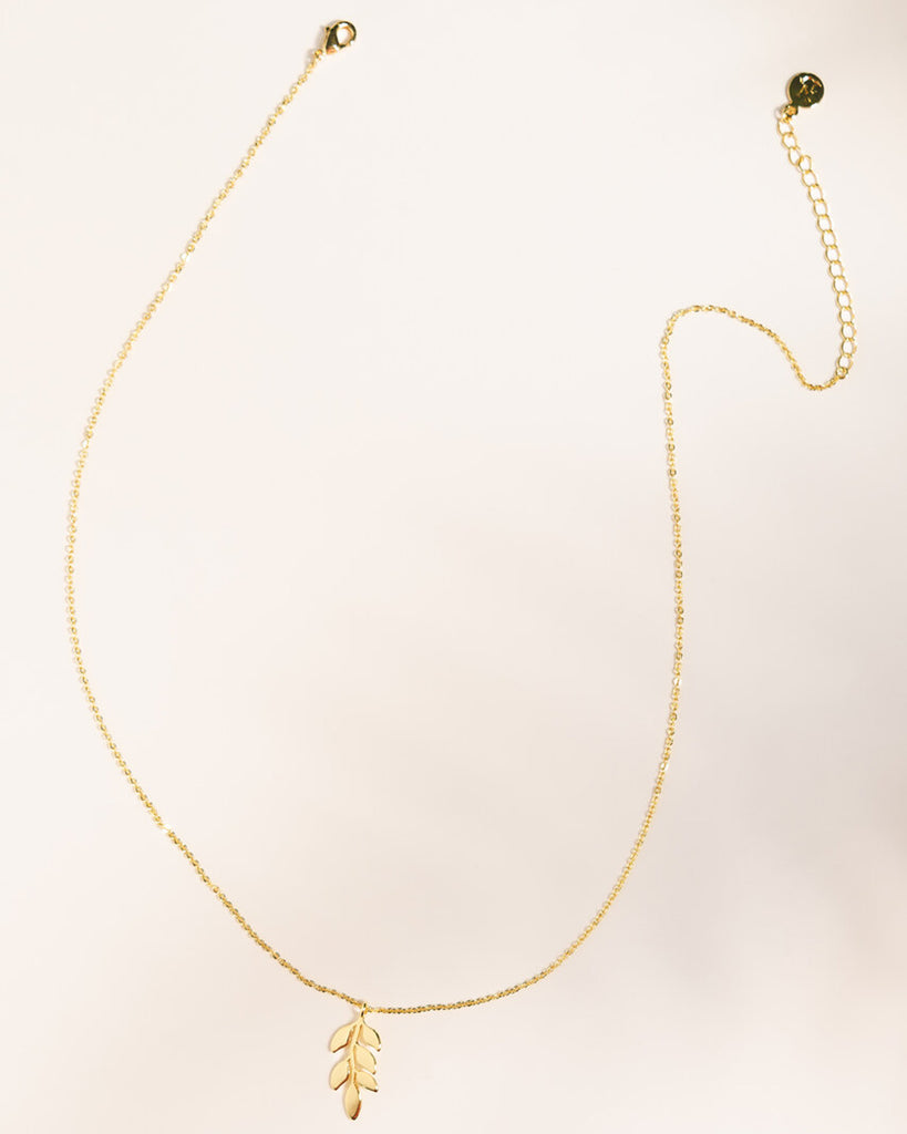 A gold necklace with a leaf pendant.