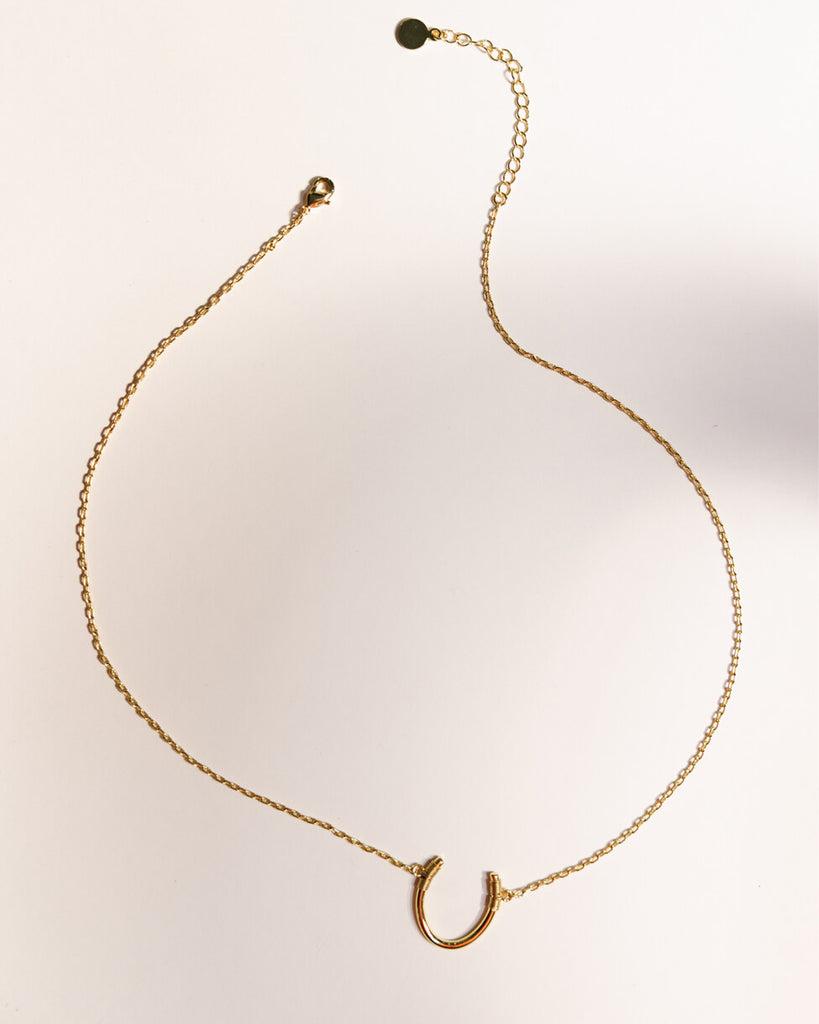 A gold necklace with a "U" shape charm.