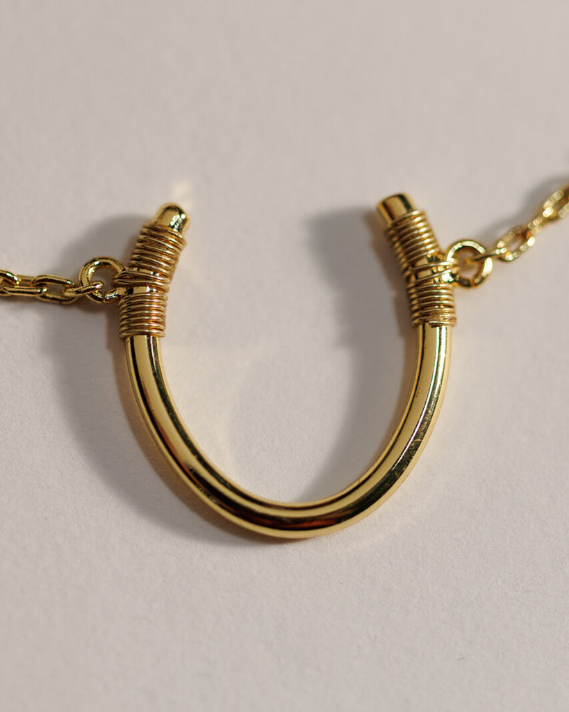 A gold necklace with a "U" shape charm.