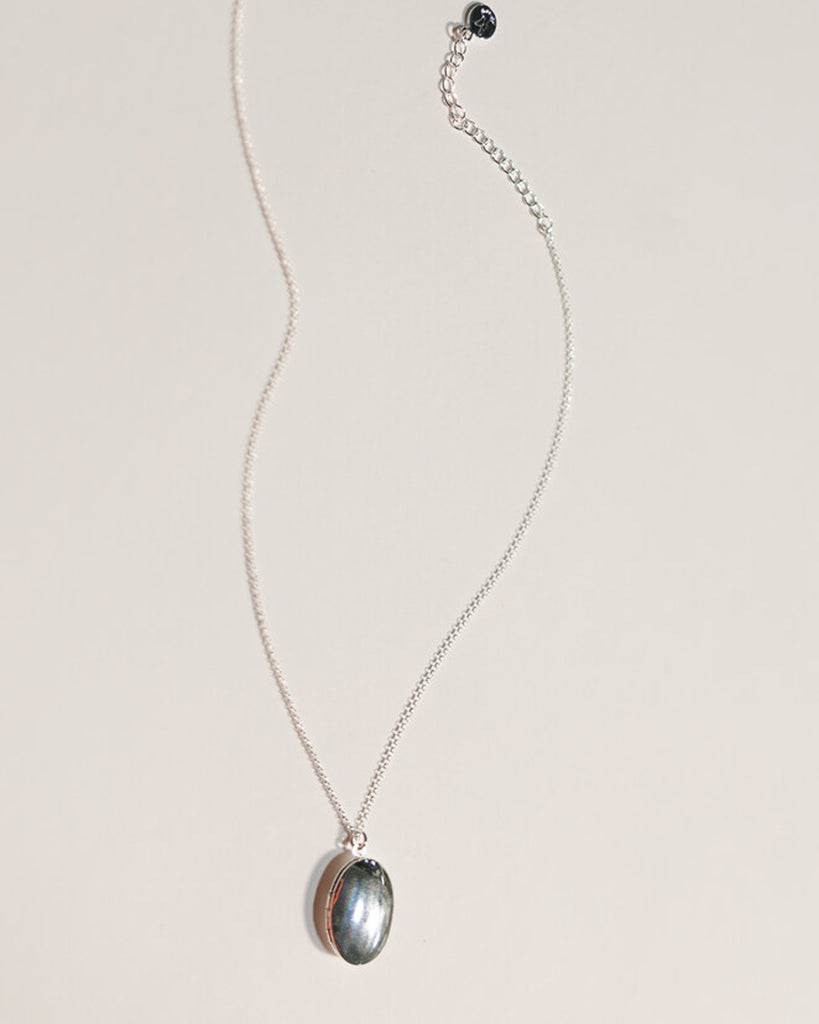 A silver necklace with an oval silver locket attached.