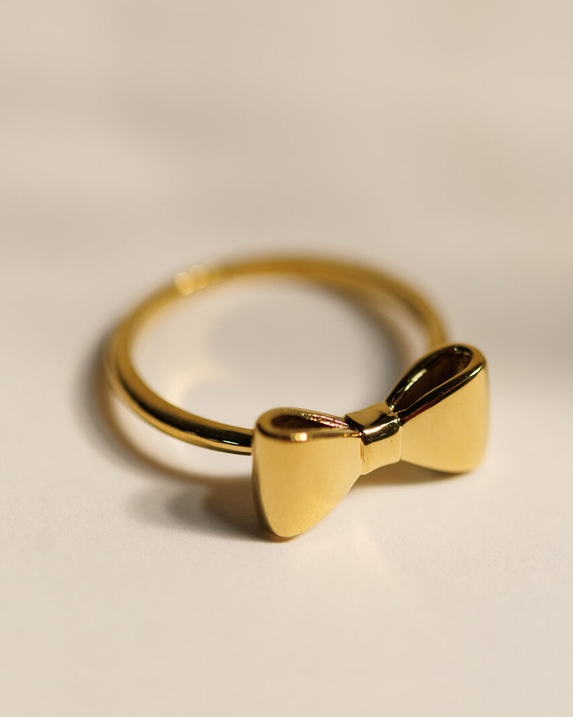 A gold ring with a bow design across the top.