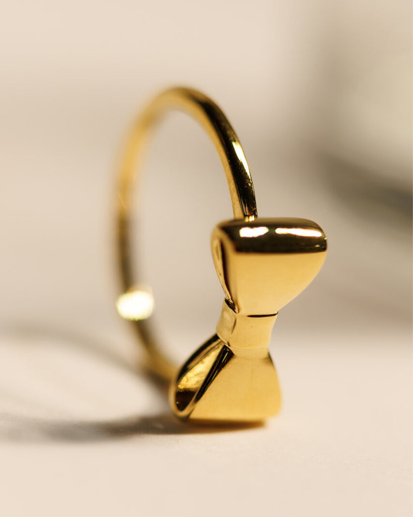 A gold ring with a bow design across the top.