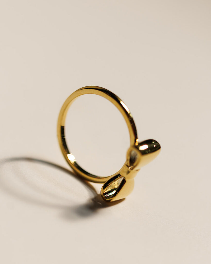 A gold ring with a bow design across the top.