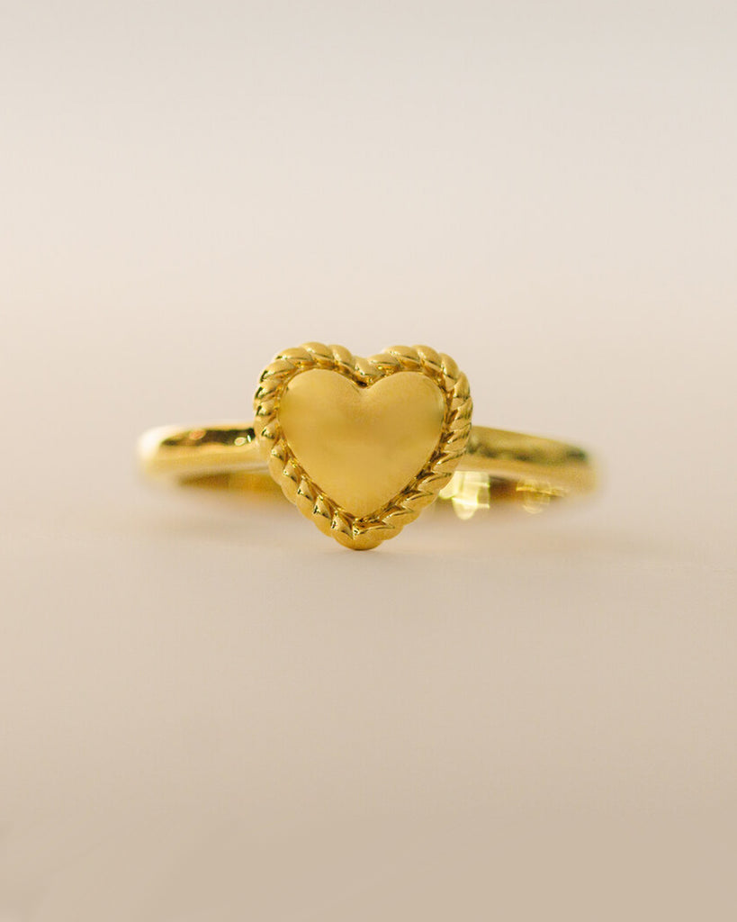 A gold ring with a heart design across the top.