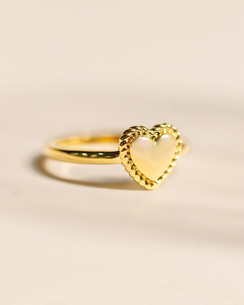 A gold ring with a heart design across the top.