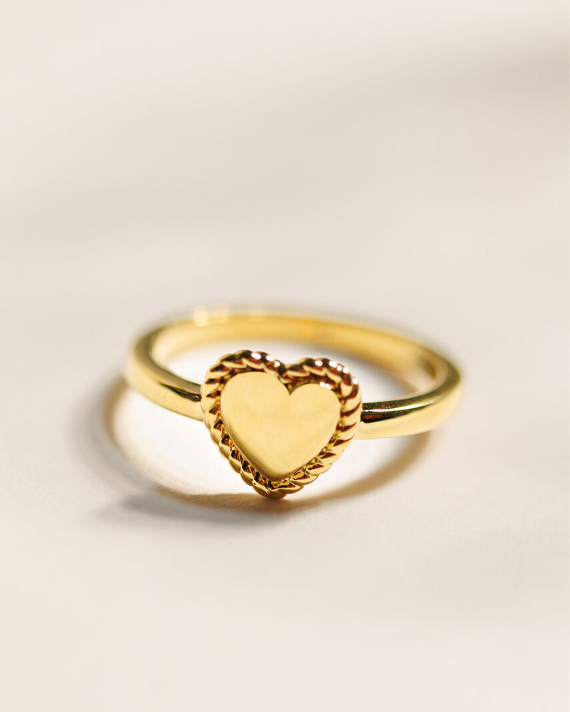 A gold ring with a heart design across the top.