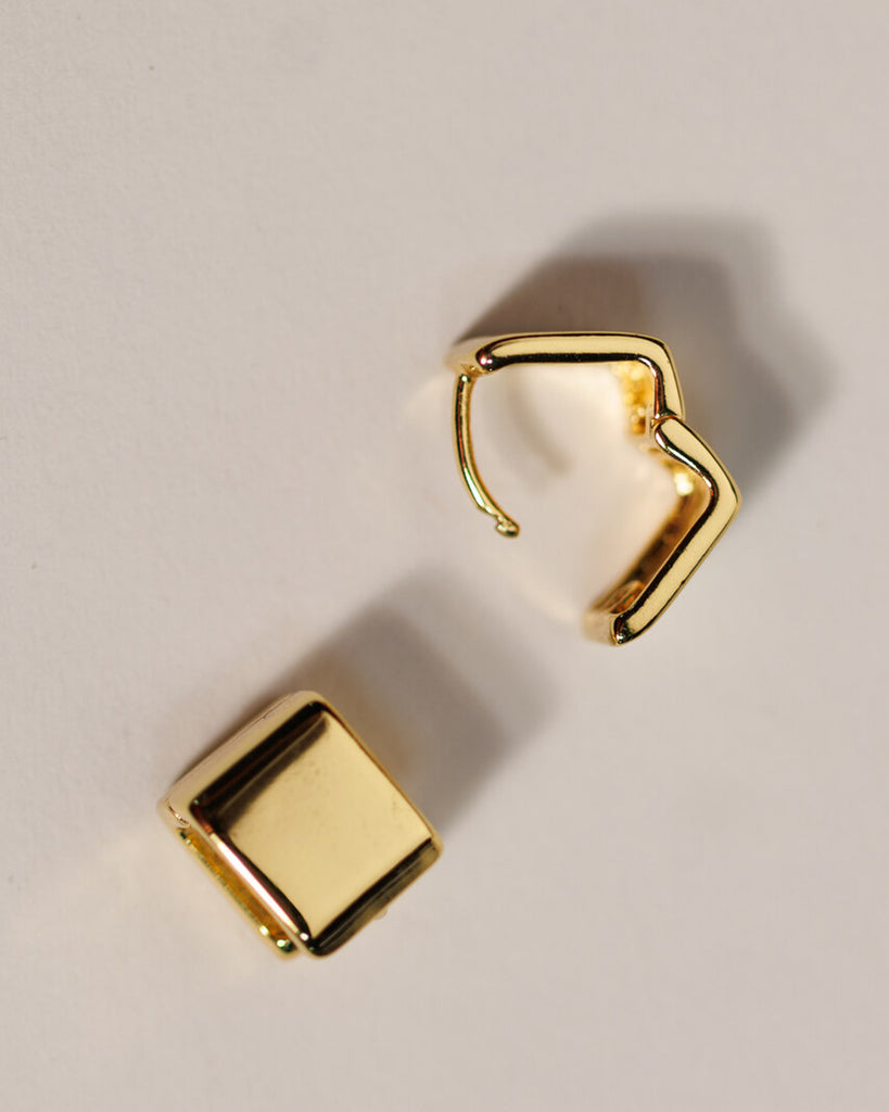 A pair of gold square huggie hoop earrings.