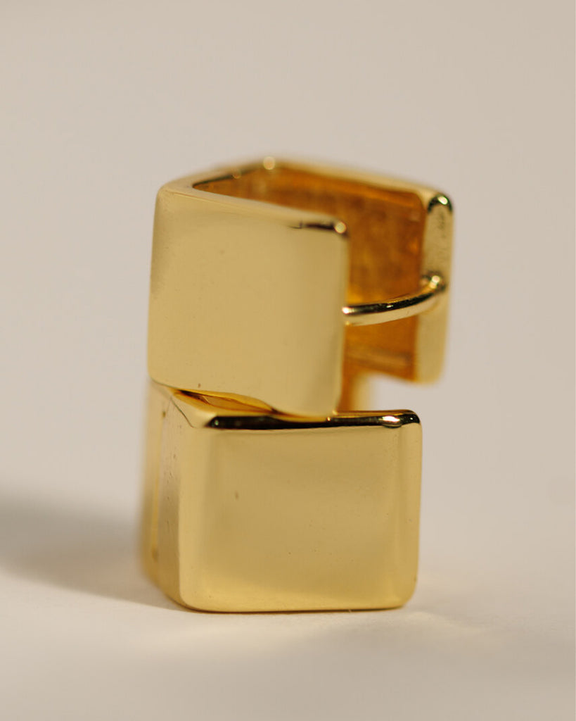 A pair of gold square huggie hoop earrings.