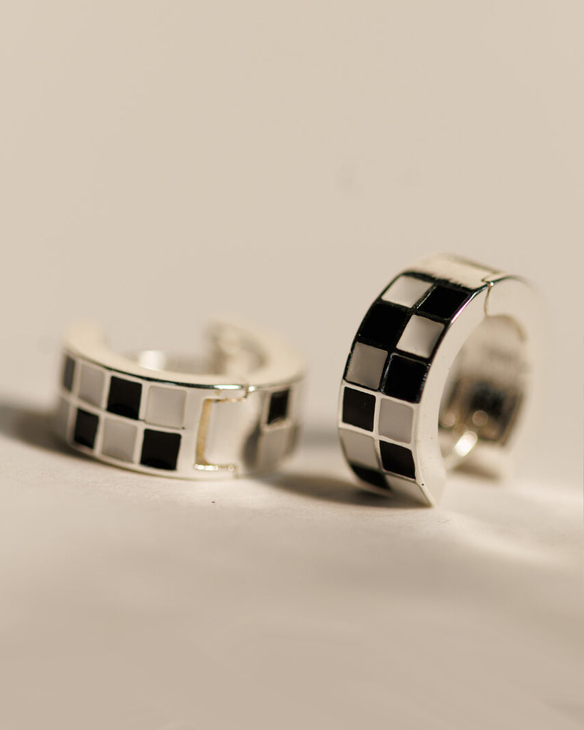 Pair of silver hoop earrings with black and white checkered pattern.