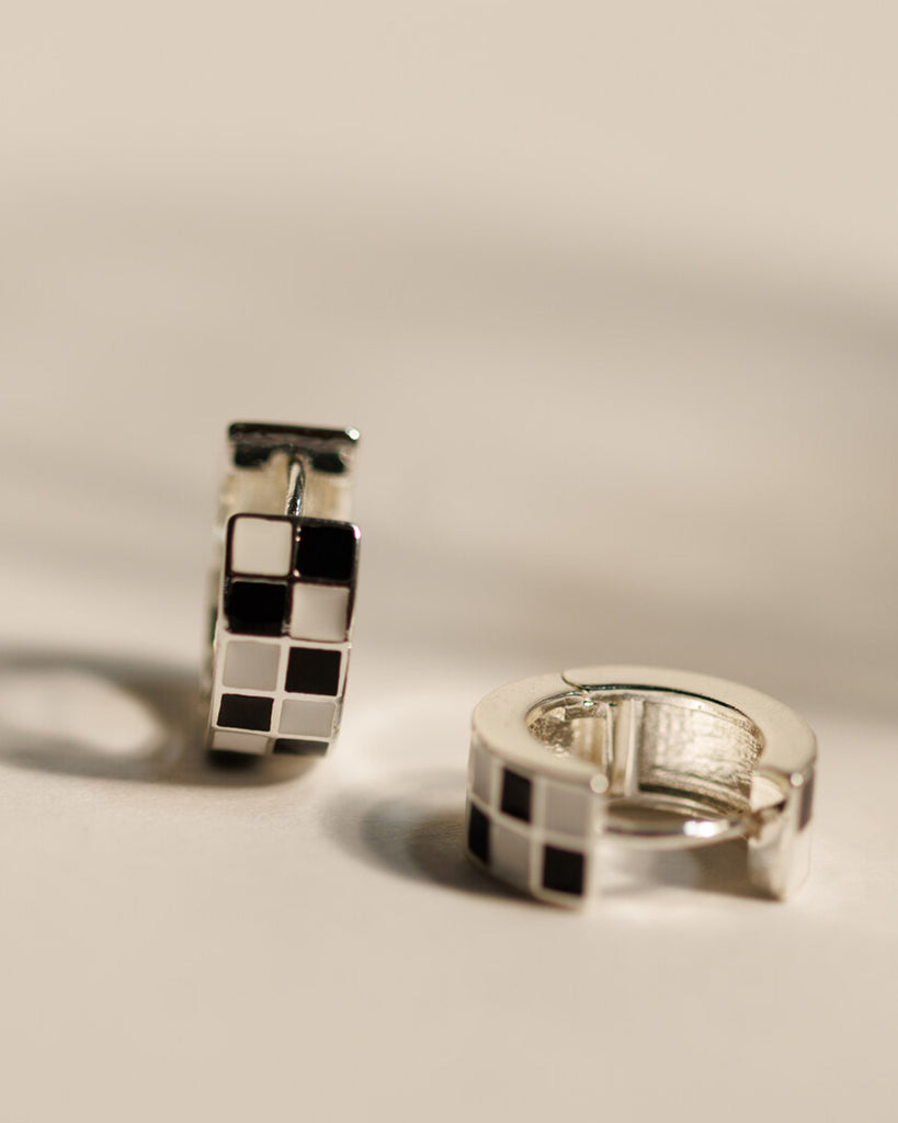 Pair of silver hoop earrings with black and white checkered pattern.