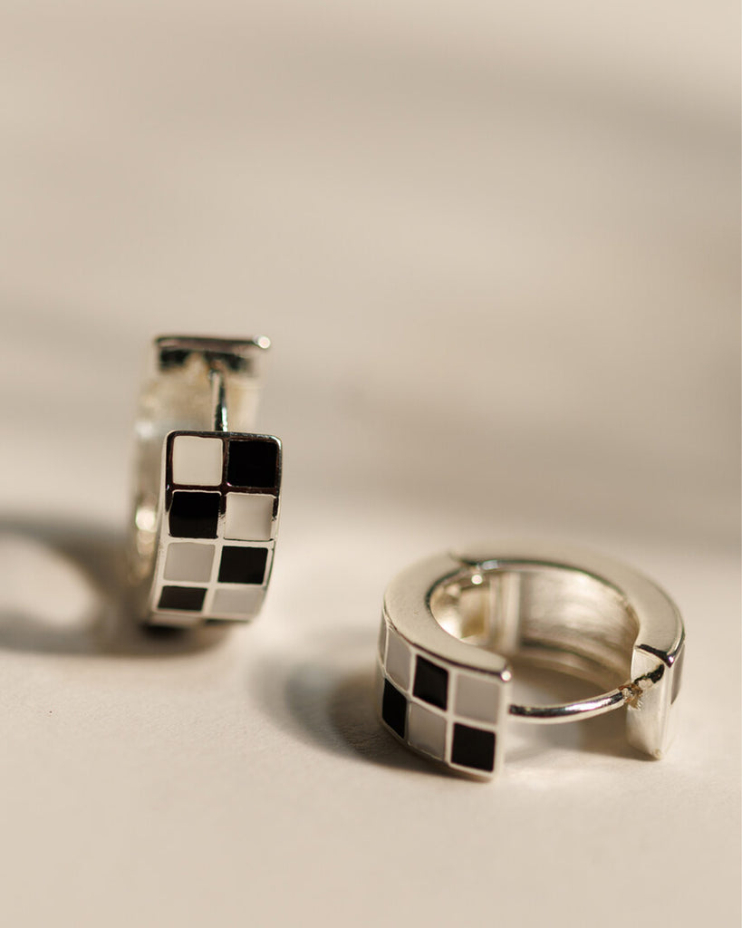 Pair of silver hoop earrings with black and white checkered pattern.