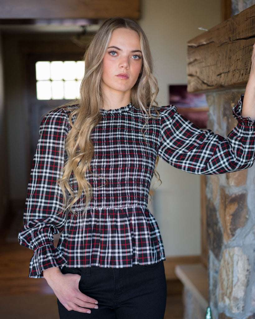 Woman in a black, white and red plaid, long sleeve peplum blouse