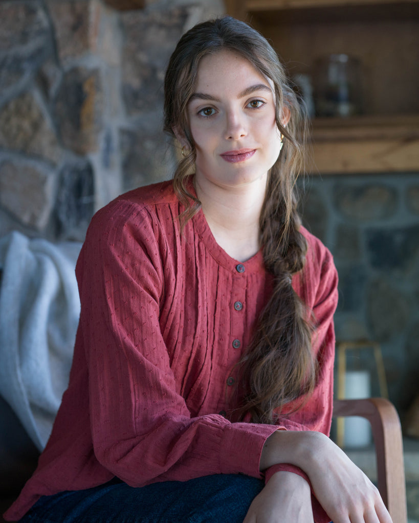 Woman in a red long sleeve blouse with dotted swiss detailing