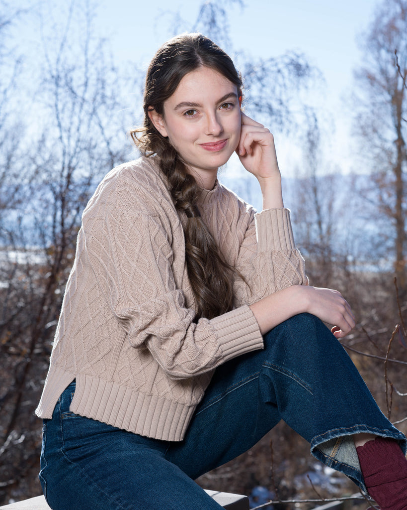 Woman in a tan cable knit long sleeve sweater