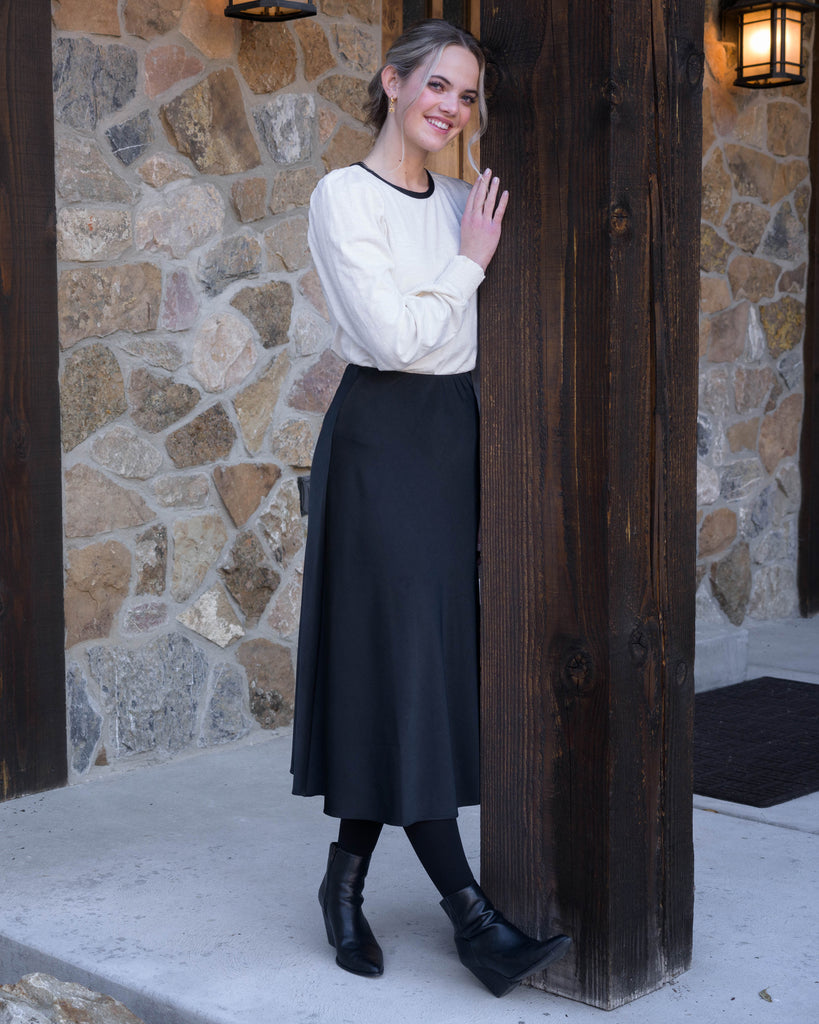 Woman in a white blouse with black detail around neckline