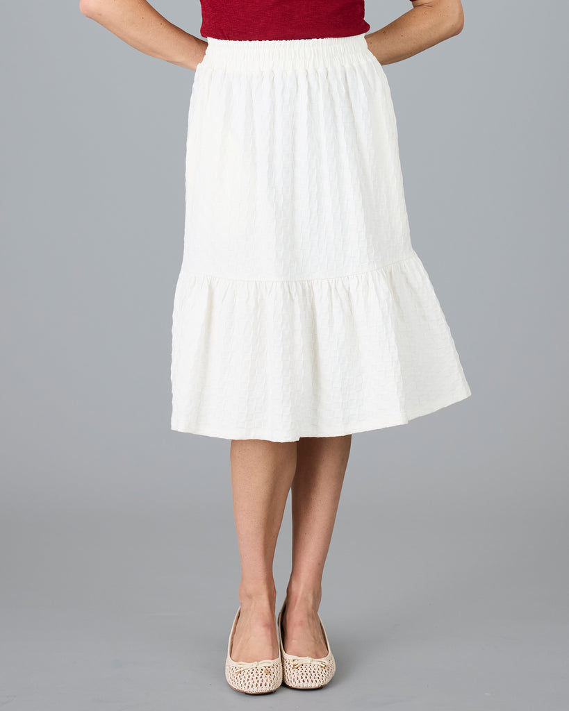 Woman in a white, knee-length textured skirt