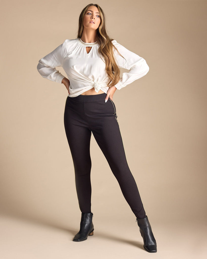 Woman in black leggings with gold piping along sides