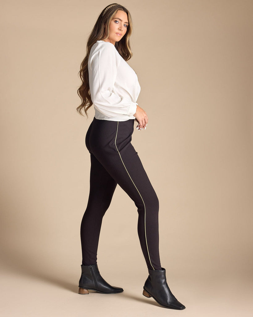 Woman in black leggings with gold piping along sides