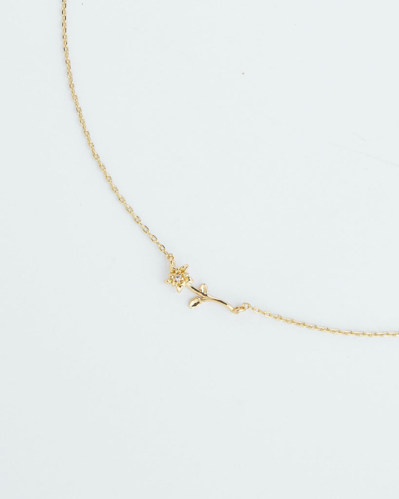 A gold necklace with a dainty flower.