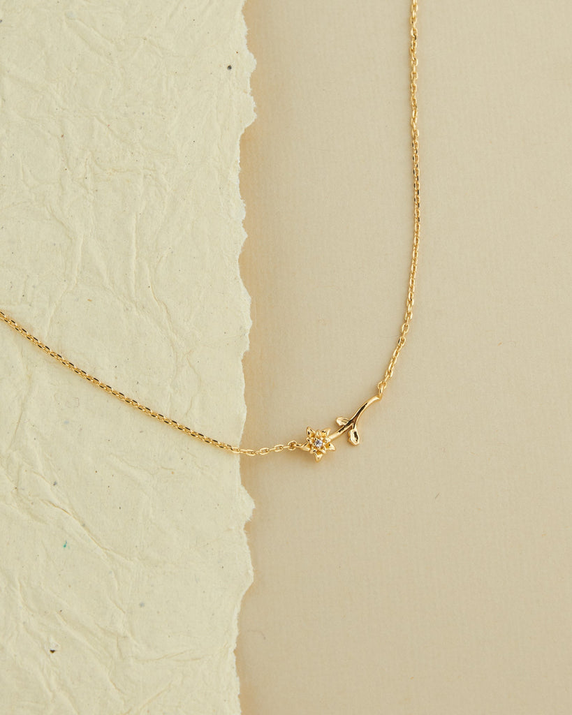 A gold necklace with a dainty flower.