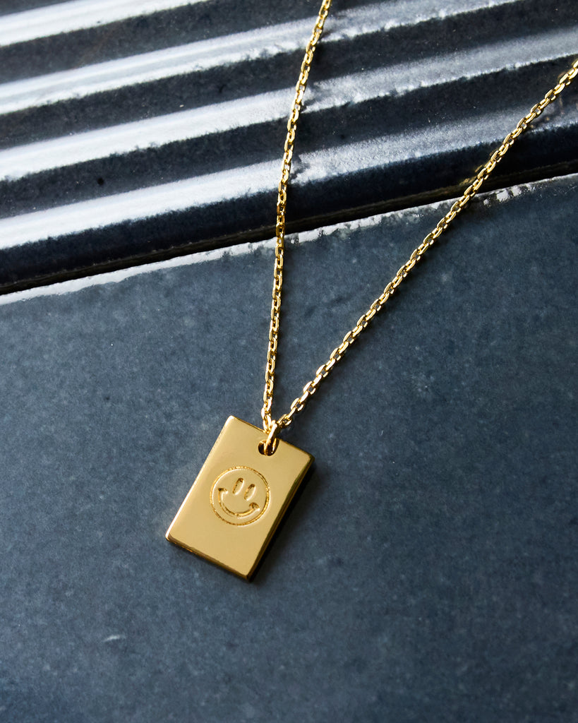 Gold necklace with smiley face pendant