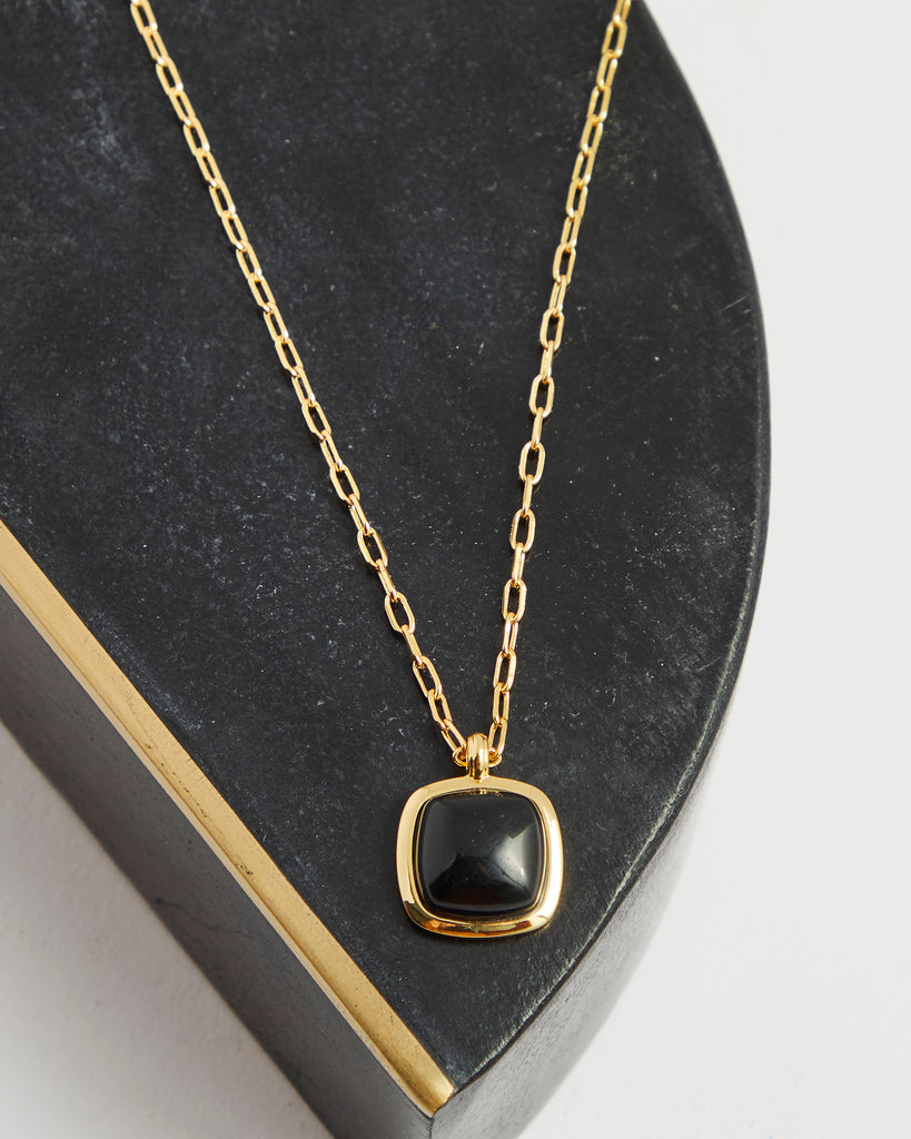 Gold chain necklace with black gem pendant