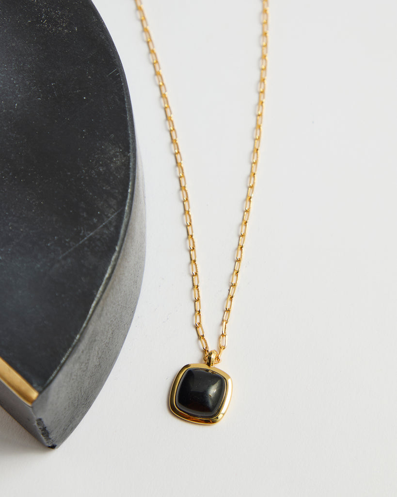 Gold chain necklace with black gem pendant