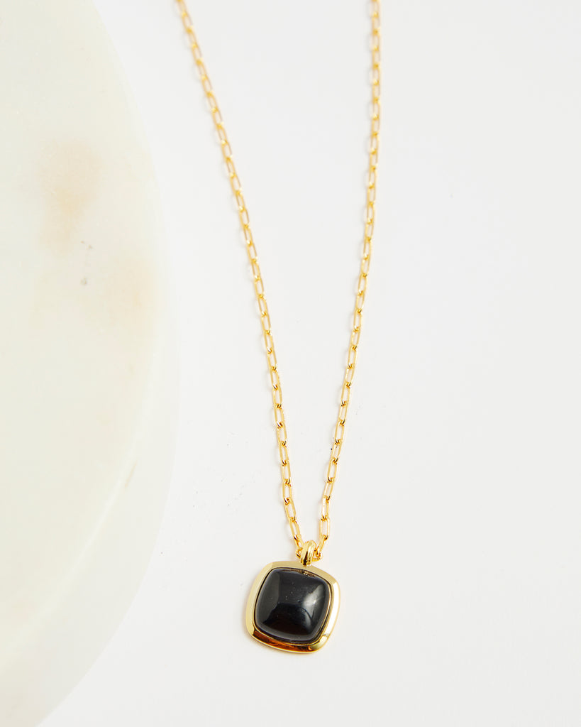 Gold chain necklace with black gem pendant