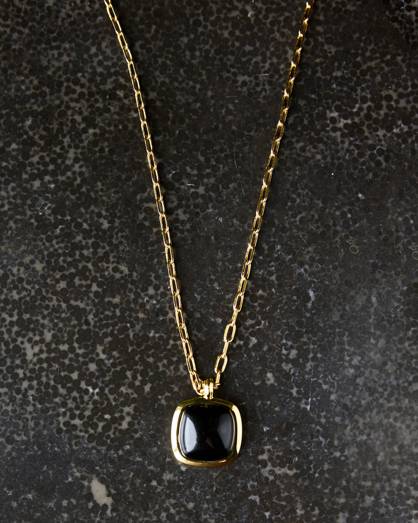 Gold chain necklace with black gem pendant