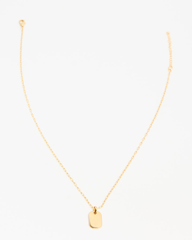 A gold necklace with a rectangular pendant attached.