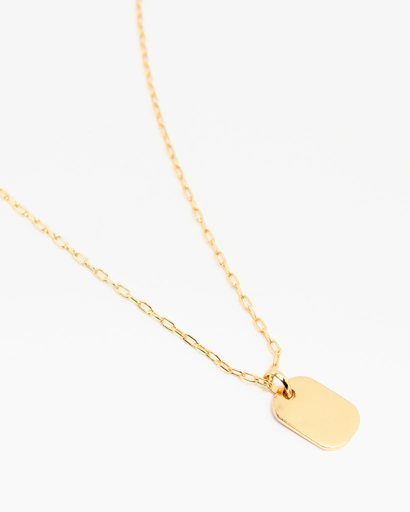 A gold necklace with a rectangular pendant attached.