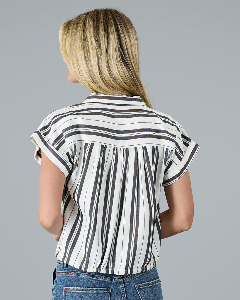 Model wearing a black and white vertical striped, short sleeved, collared, button-up blouse.