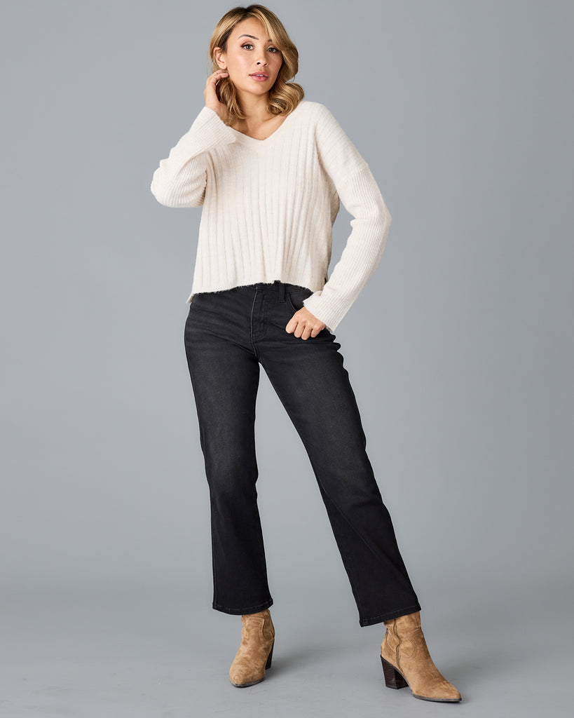 Model wearing a white long sleeve, v-neck, ribbed sweater