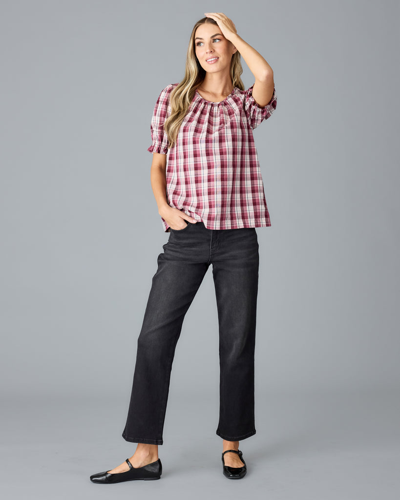 Model wearing a red and white plaid short sleeve, scoop neck blouse.