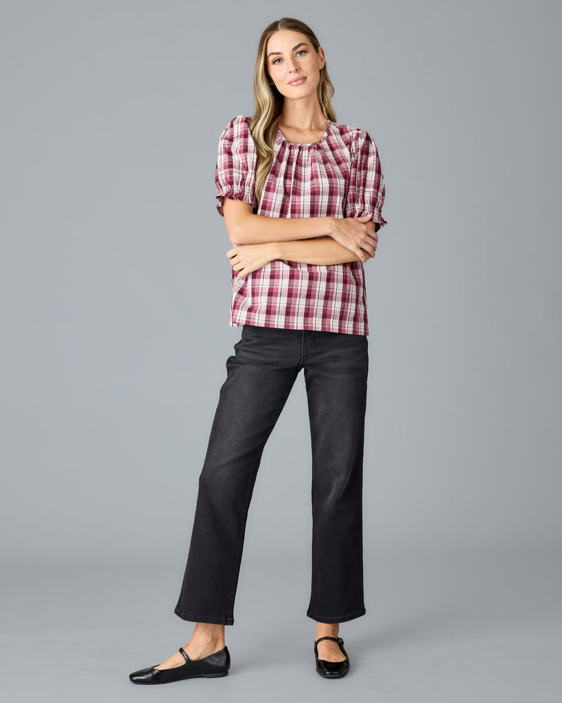 Model wearing a red and white plaid short sleeve, scoop neck blouse.