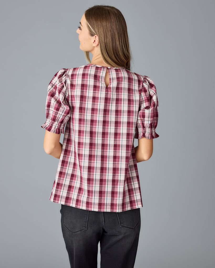 Model wearing a red and white plaid short sleeve, scoop neck blouse.