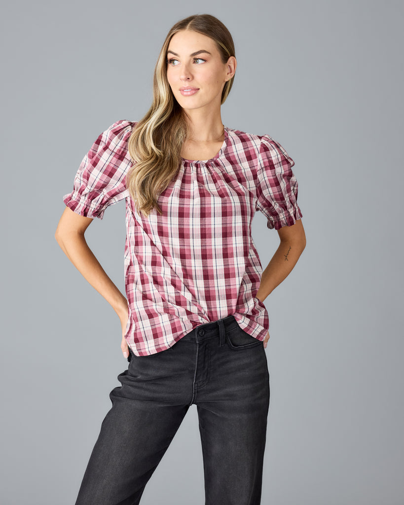 Model wearing a red and white plaid short sleeve, scoop neck blouse.