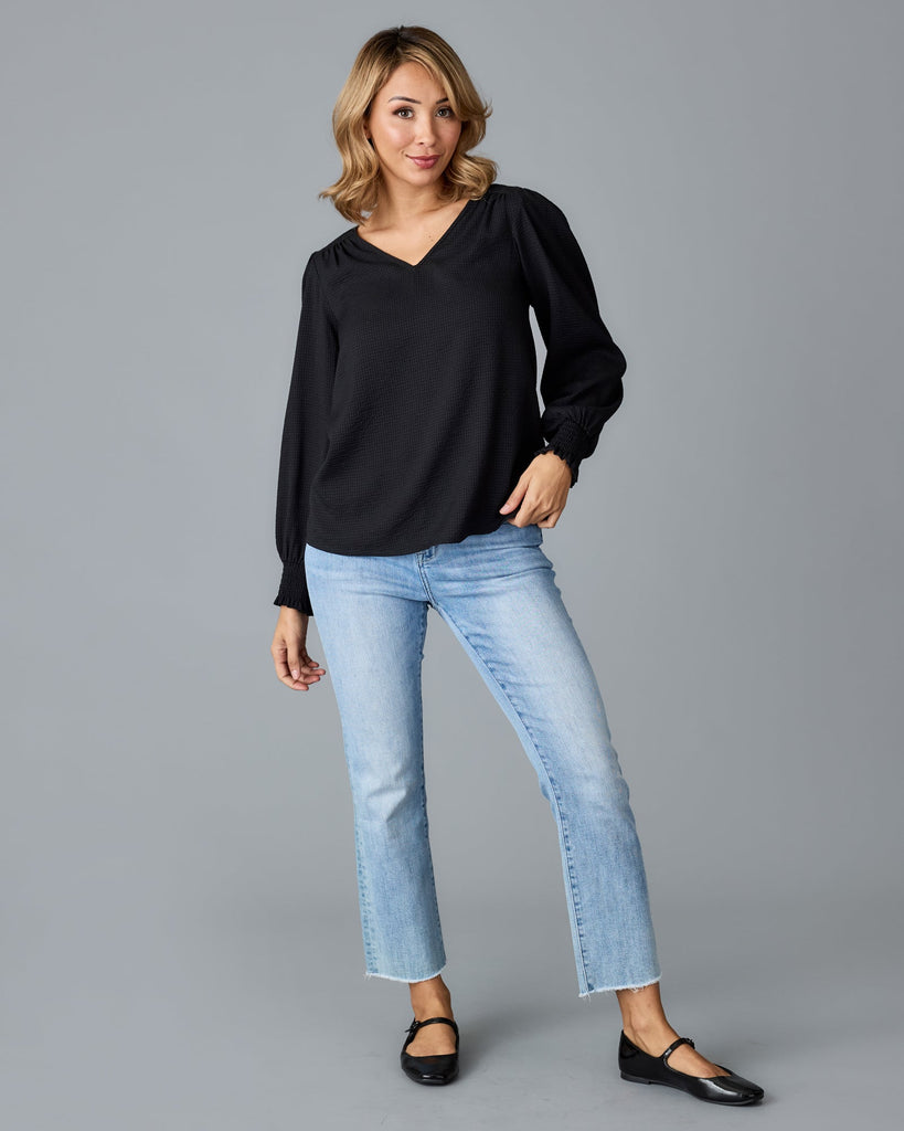 Model wearing a black long sleeve, v-neck loose fitting blouse.