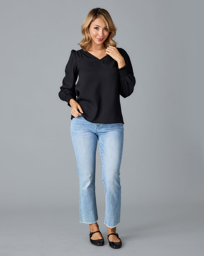 Model wearing a black long sleeve, v-neck loose fitting blouse.