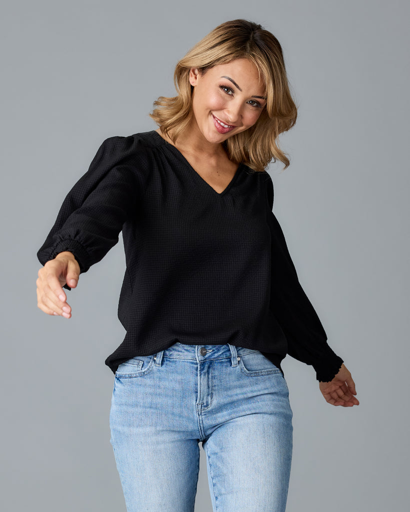 Model wearing a black long sleeve, v-neck loose fitting blouse.