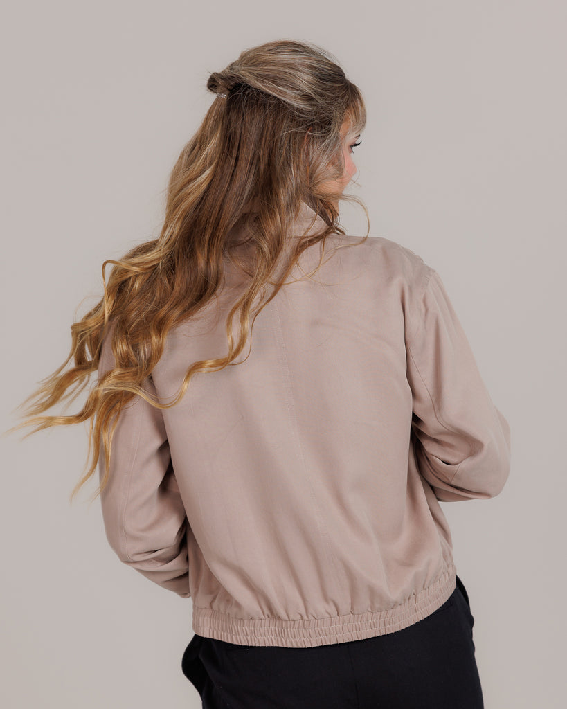 Model wearing a tan long sleeve, collared, lightweight jacket.