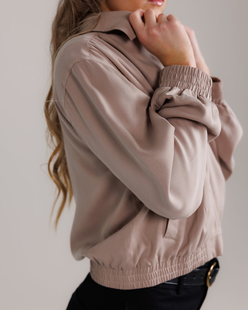 Model wearing a tan long sleeve, collared, lightweight jacket.