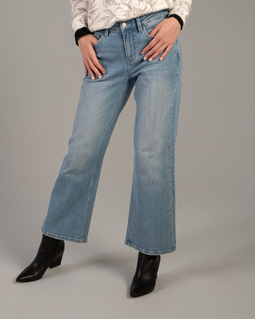 Model wearing light blue flared ankle length jeans.