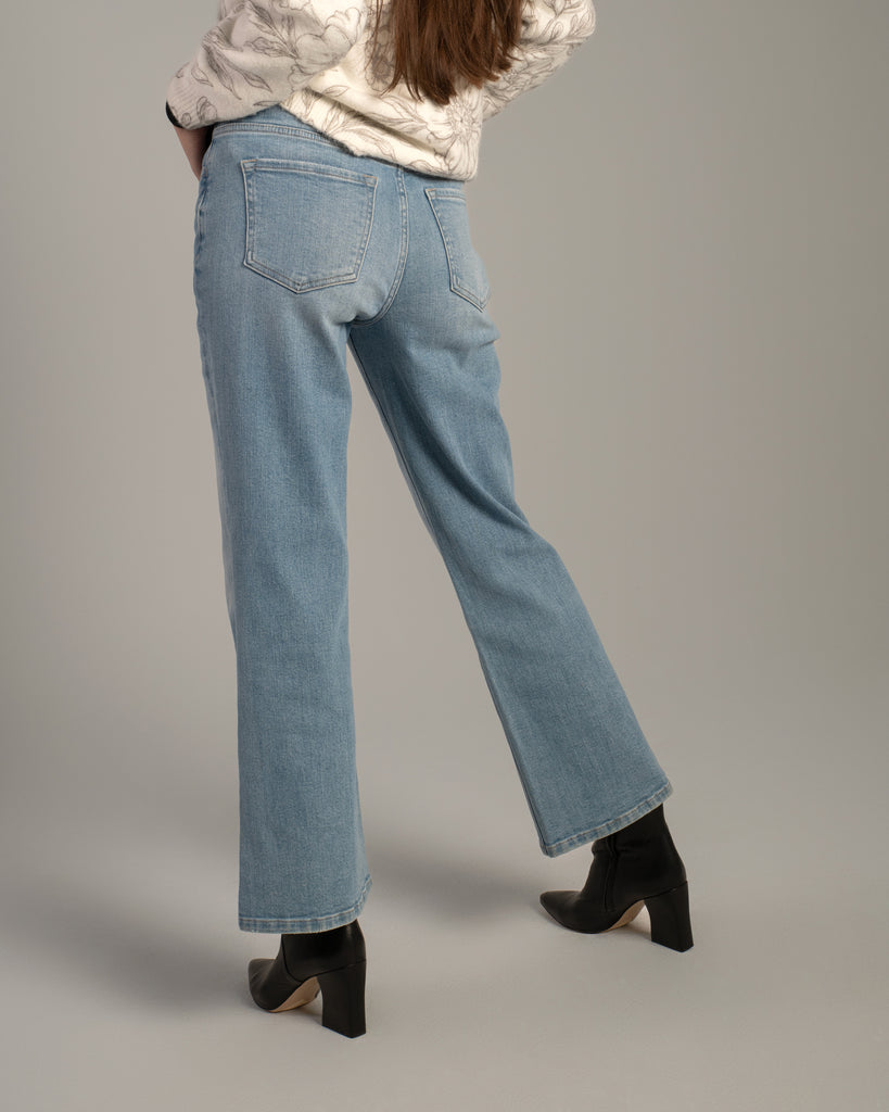 Model wearing light blue flared ankle length jeans.