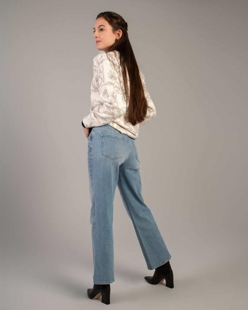 Model wearing light blue flared ankle length jeans.