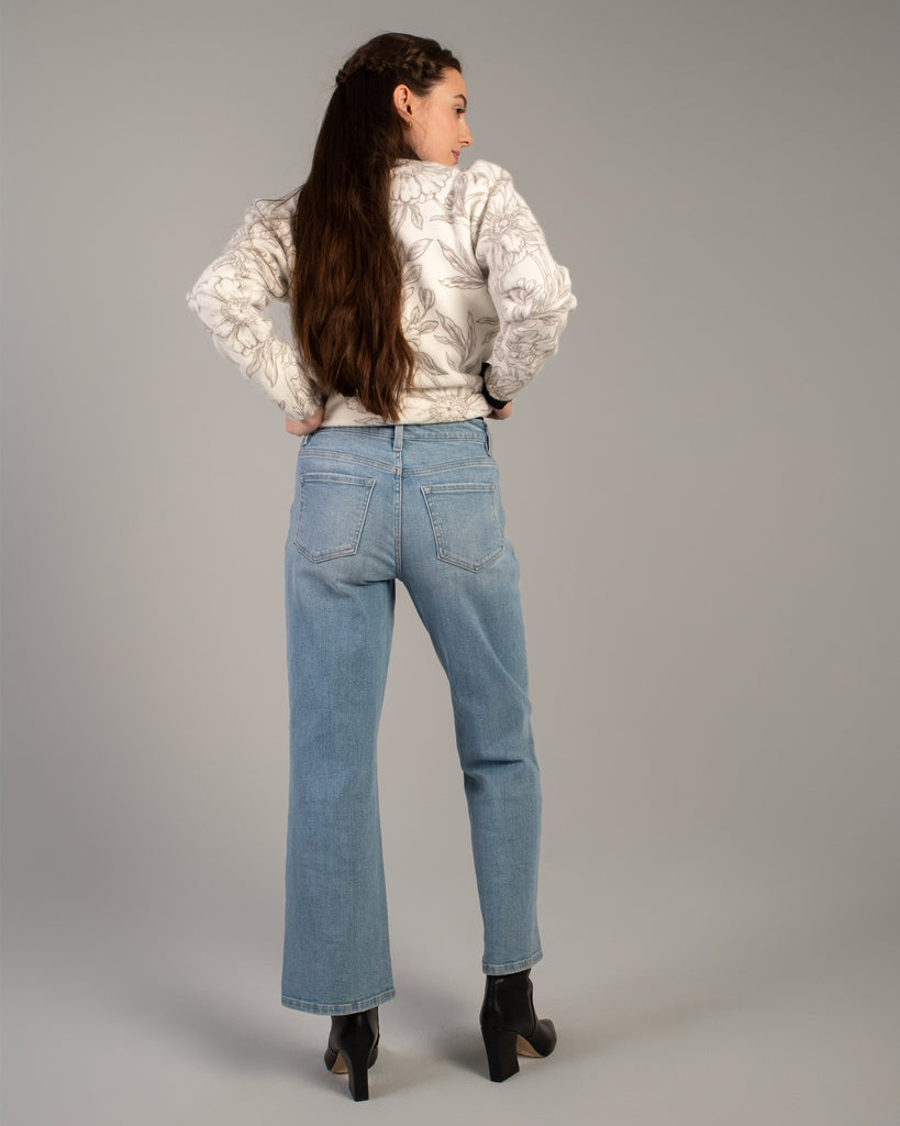 Model wearing light blue flared ankle length jeans.