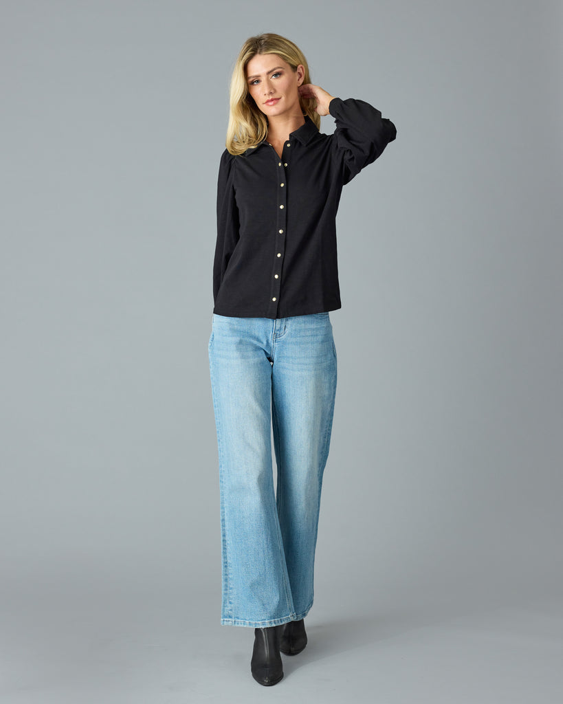 Woman in a black, long sleeve, collared buttondown top