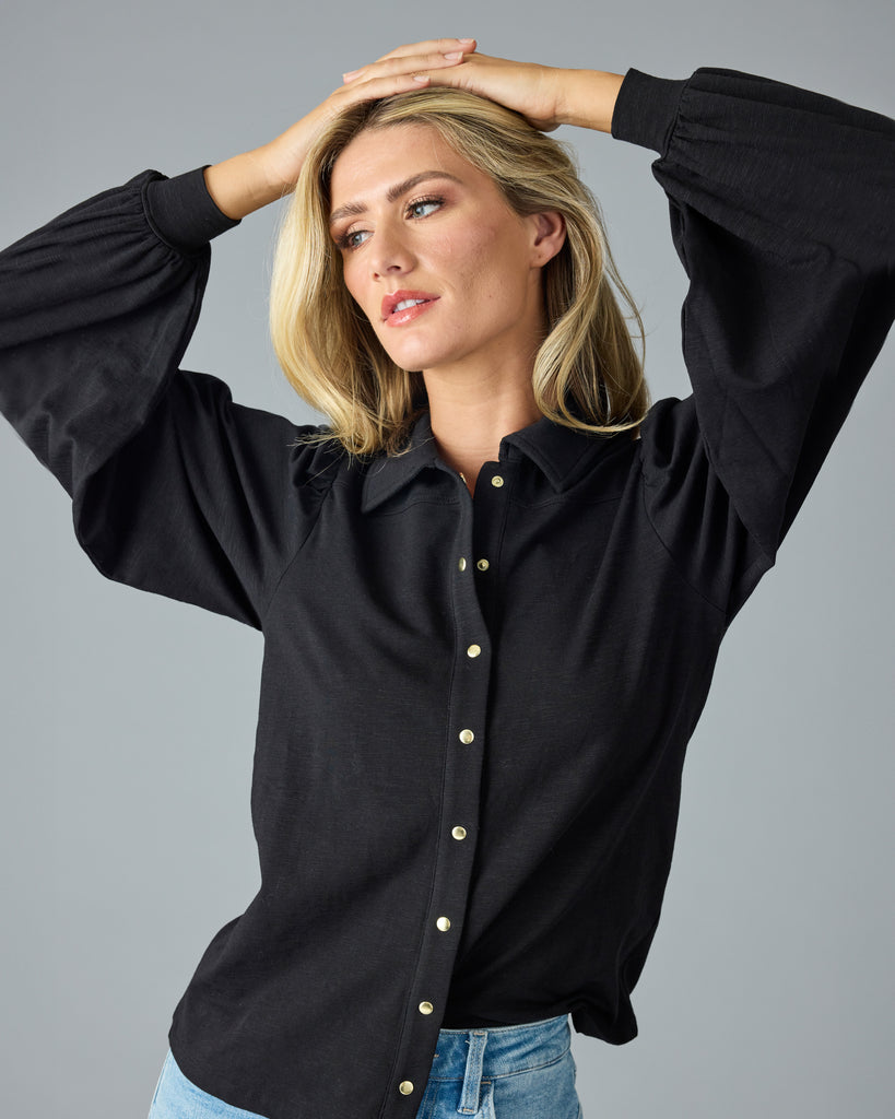 Woman in a black, long sleeve, collared buttondown top