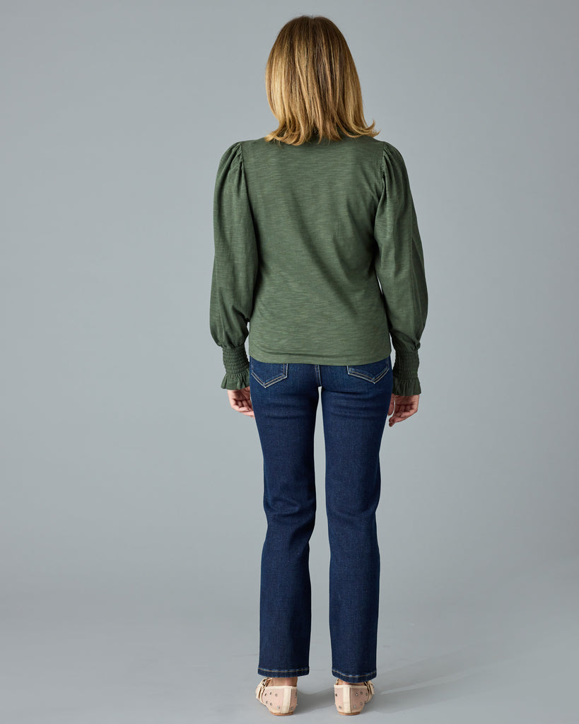 Woman in a green, long sleeve tshirt with ruffle details on sleeve